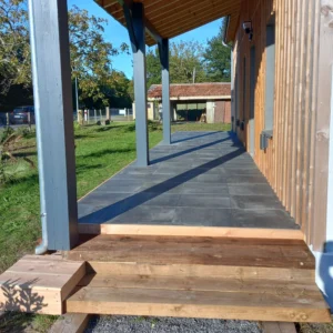 Photo d'une terrasse sur plots avec du carrelage gris foncé.