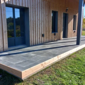 Photo d'une terrasse sur plots avec du carrelage gris foncé.