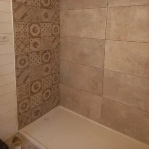 Photo d'une salle de bain avec du carrelage mural et un bac à douche.