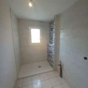 Photo d'une salle de bain avec des murs en carrelage blanc et mosaïque avec un bac à douche blanc.