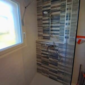 Photo d'une salle de bain avec des murs en carrelage blanc et mosaïque avec un bac à douche blanc et une paroi de douche.